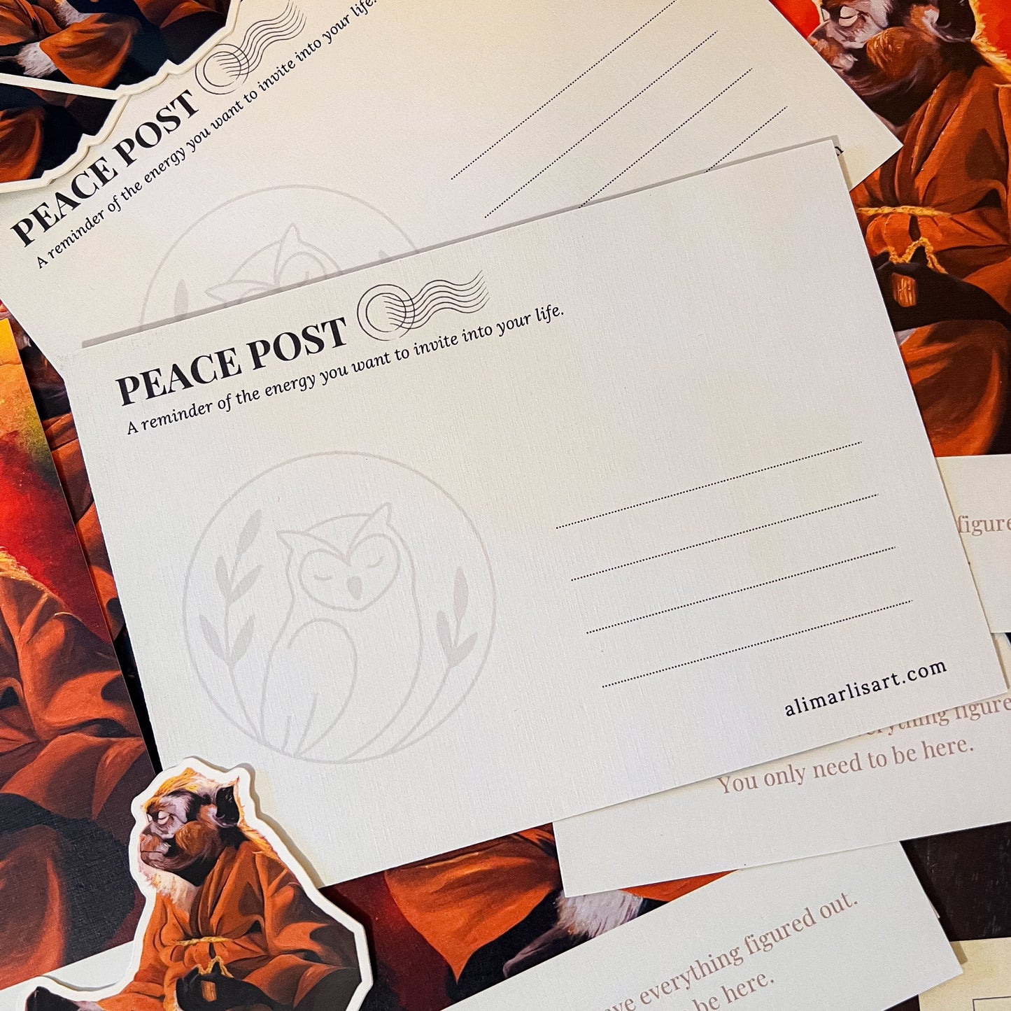 A set of white 'Peace Post' cards with printed text and line guides, scattered over a background of orange and black illustrated cards featuring a seated figure.